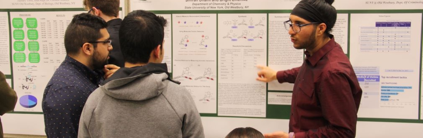 Three male students reviewing a poster presentation