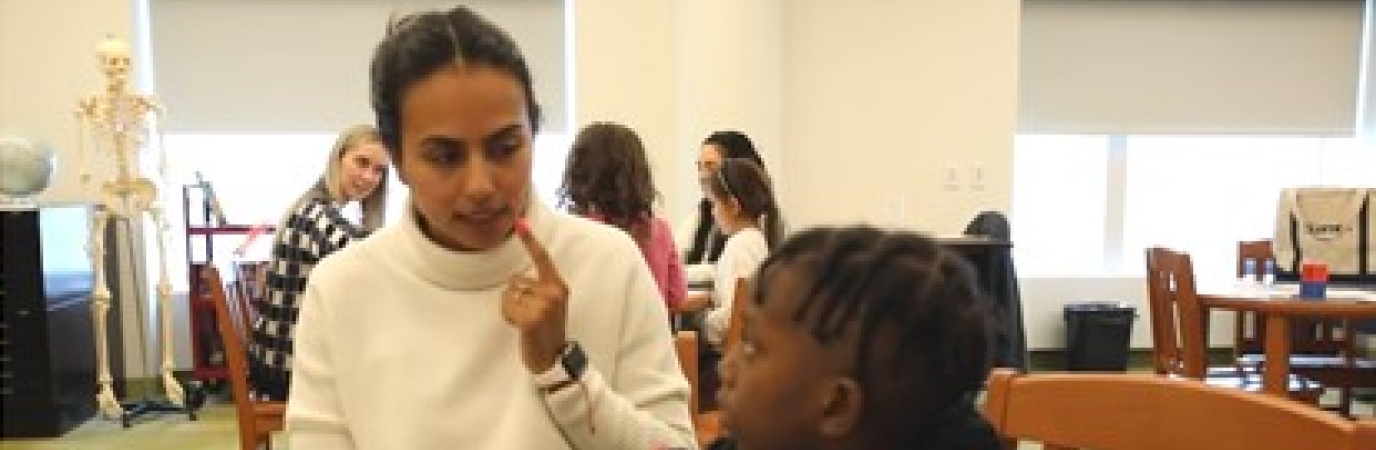 Student teacher works with make child at a table