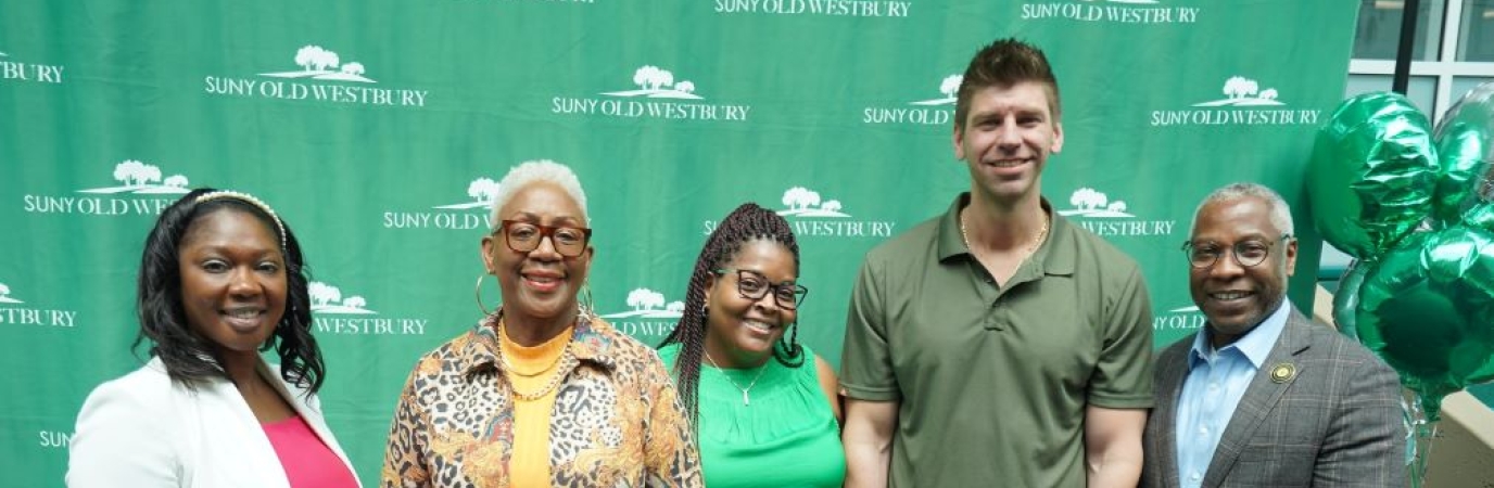 Three female and one male graduate with the college president
