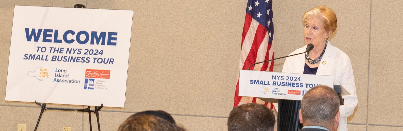 Woman at podium next to sign reading Welcome the 2024 Small Business Intragency Tour