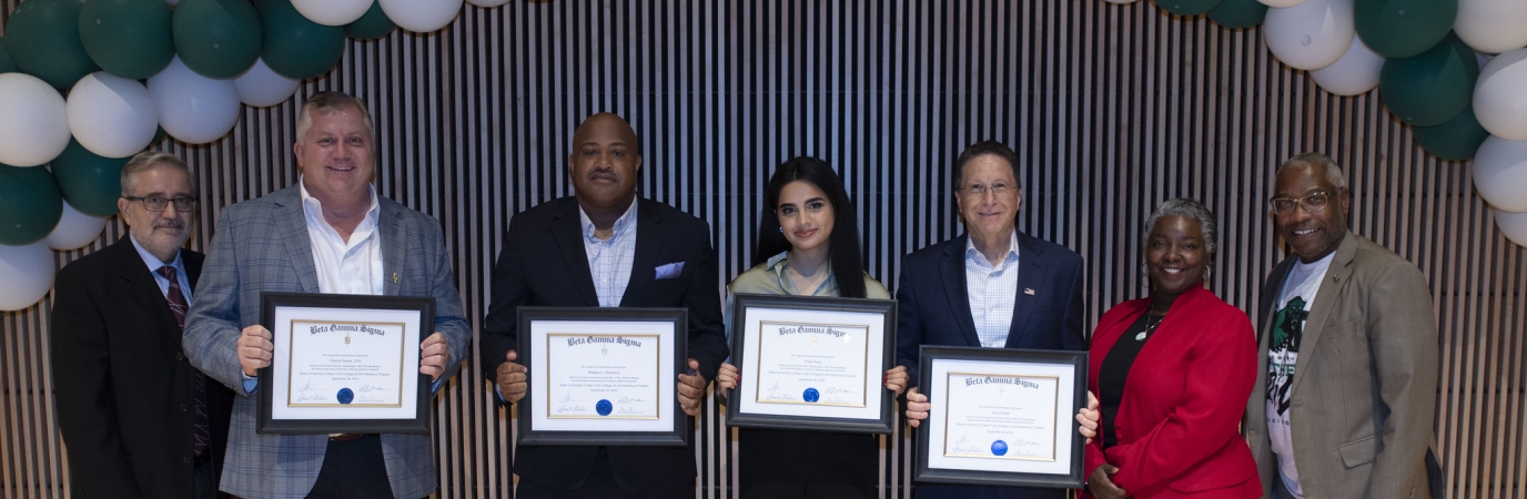 Four awardees holding certificates are congratulated by three campus officials