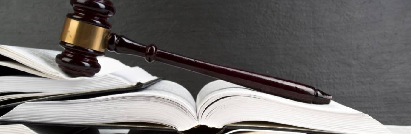 A gavel laying on a stack of opened books