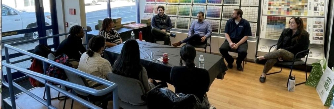 Eight people sit around a conference table talking