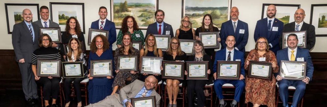 21 people in business attire pose with their awards