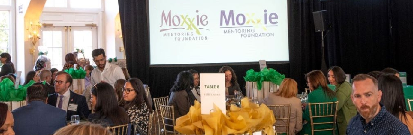 Crowded ballroom with signs for Moxxie Foundation