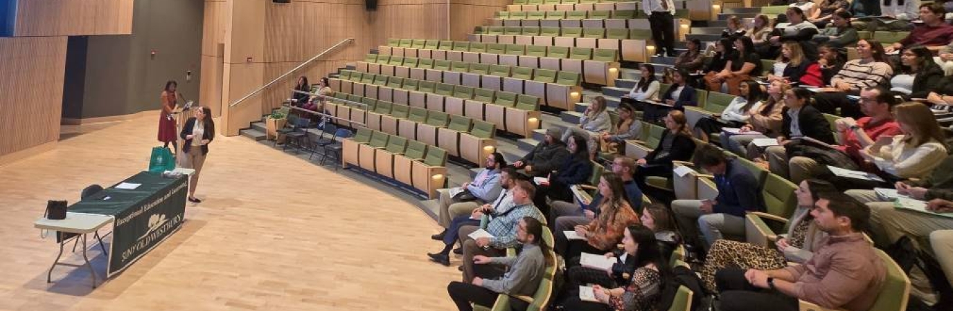 An audience gathers to hear from a female speaker