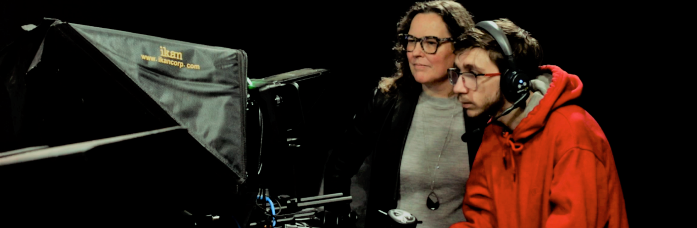 Female professor with male student using studio camera