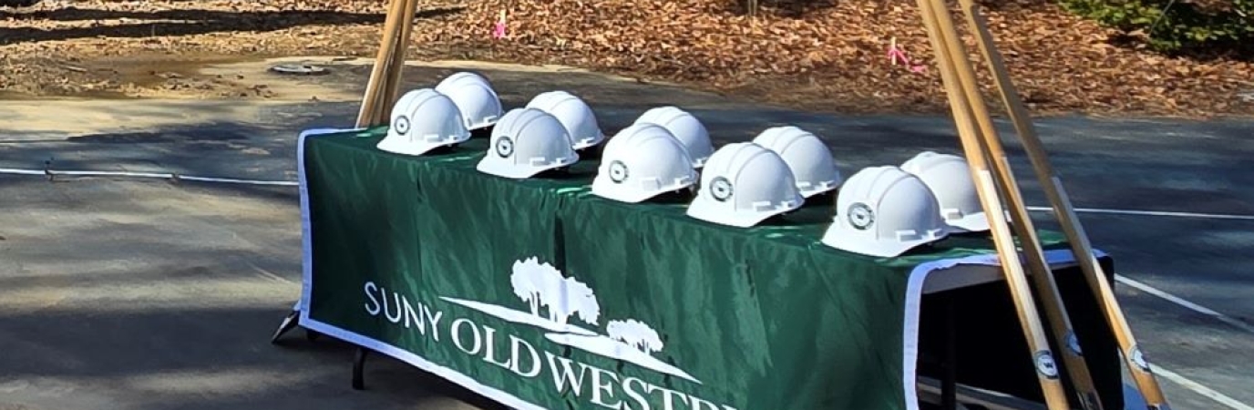 Hard hats on a table with shovels leaning against the table
