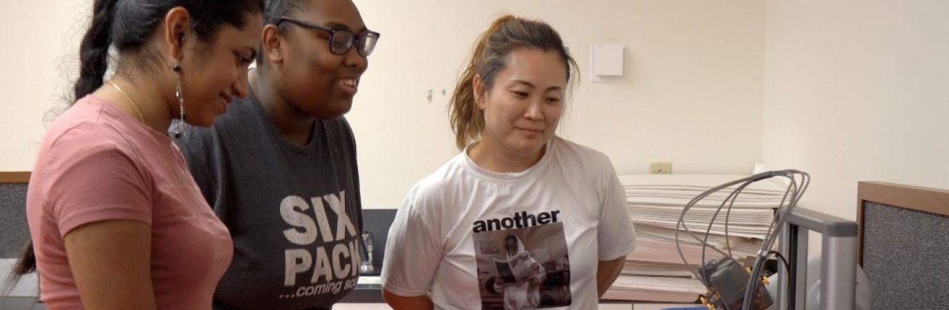 Three women working with a 3D printer