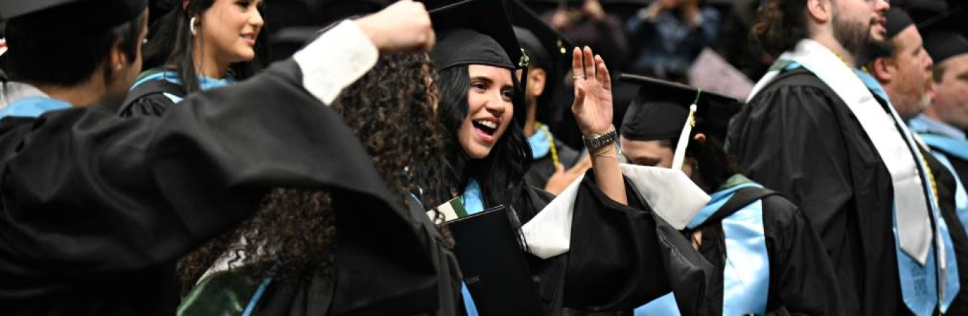 Five students in regalia moving the tassel on their mortarboards