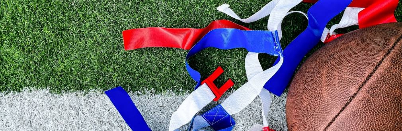 football and blue and red flags laying on a green turf field