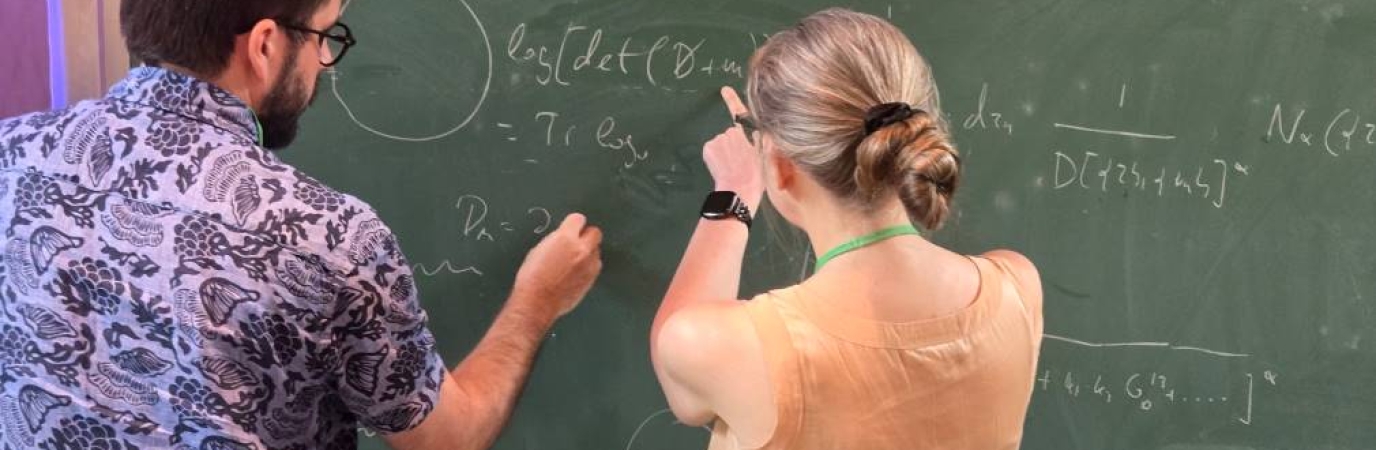 Two professors work together on a chalkboard