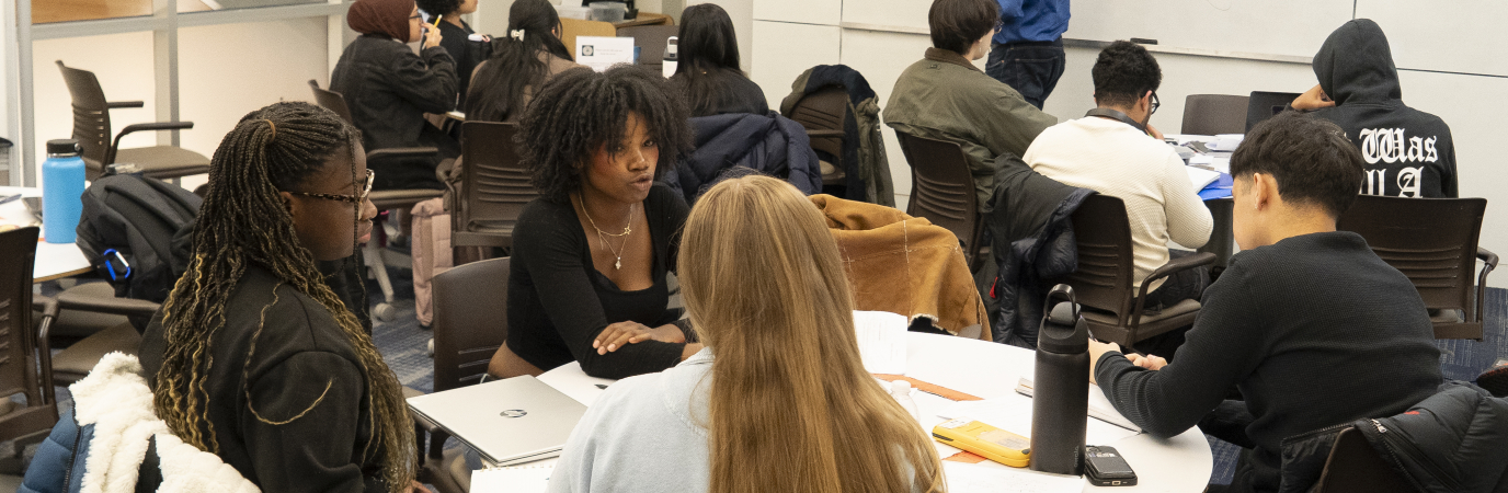 Students sitting at a round table with math tutors