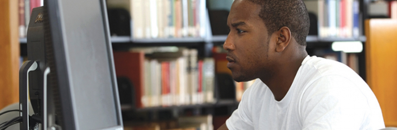 A black male student looking at computer monitor