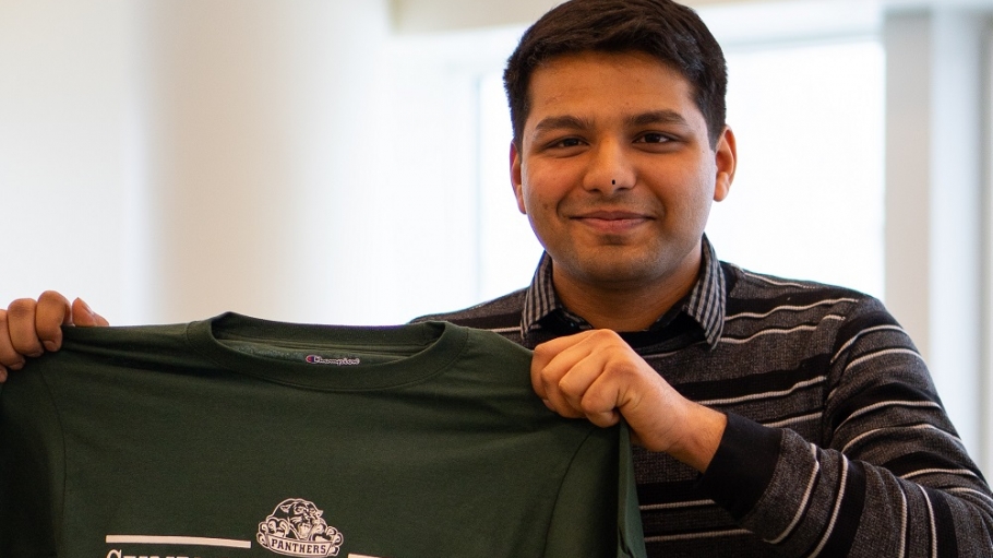 Drumil Shah holding an Old Westbury Alumni t-shirt