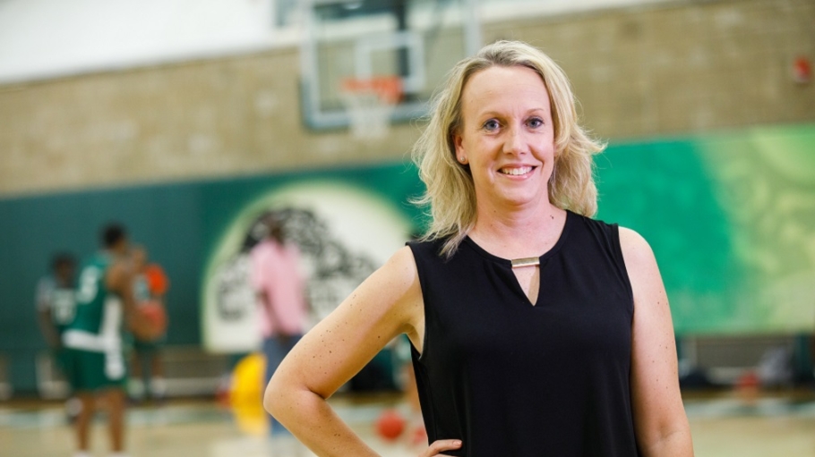 Lenore Walsh in black dress standing in Clark Center Fieldhouse