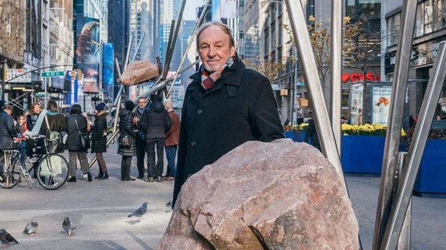 man in coat standing near stone sculpture