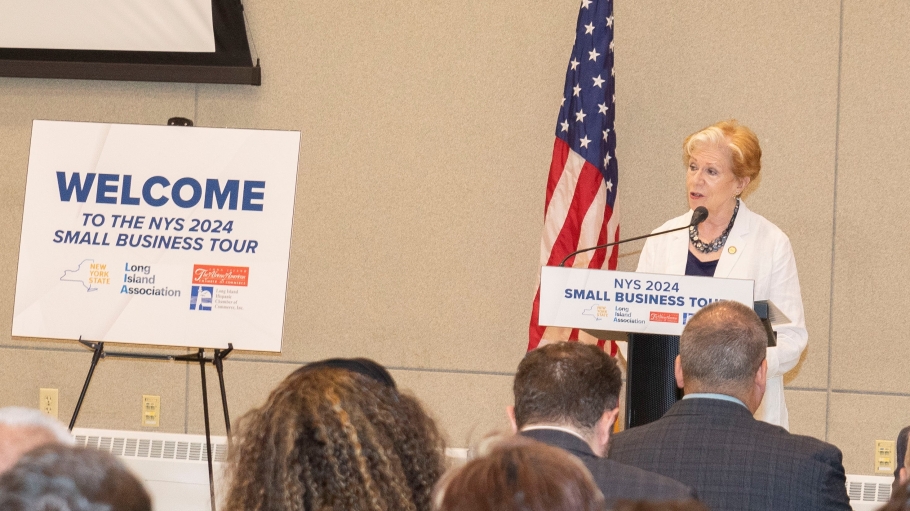 Woman at podium next to sign reading Welcome the 2024 Small Business Intragency Tour