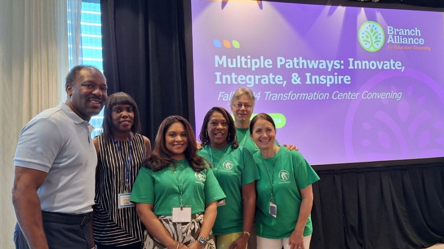 Five professionals stand before a sign reading "Multiple Pathways: Innovate, Integrate & Inspire"