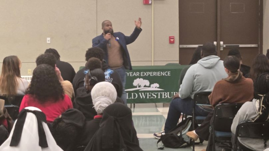 African American man stands and speaks before an audience of young people