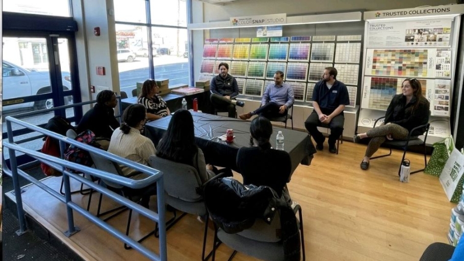 Eight people sit around a conference table talking