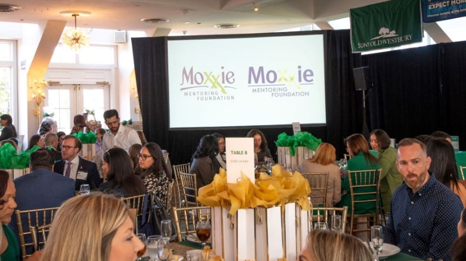 Crowded ballroom with signs for Moxxie Foundation