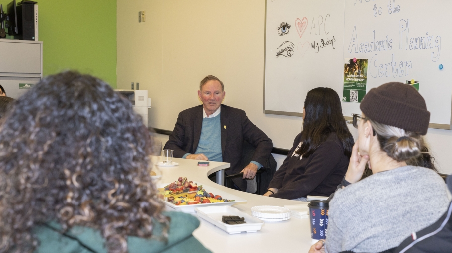 Man sits at conference table with young female students