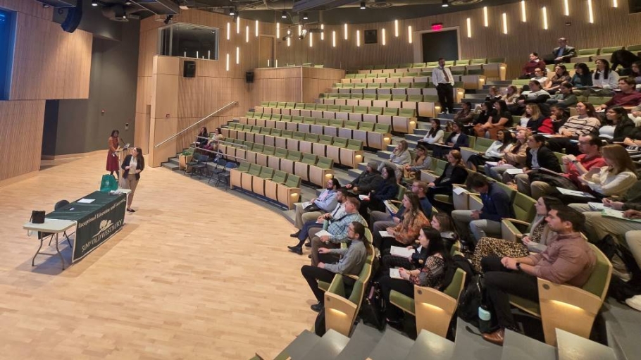 An audience gathers to hear from a female speaker