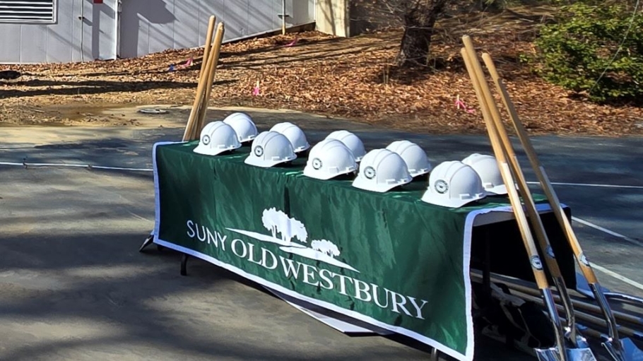 Hard hats on a table with shovels leaning against the table