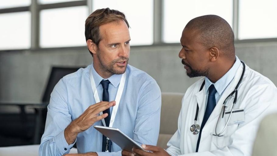Man in professional dress speaks with man in doctor's garb