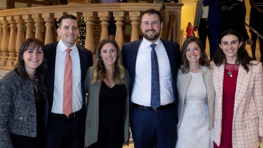 Four women and two mean in business dress smiling for the photographer