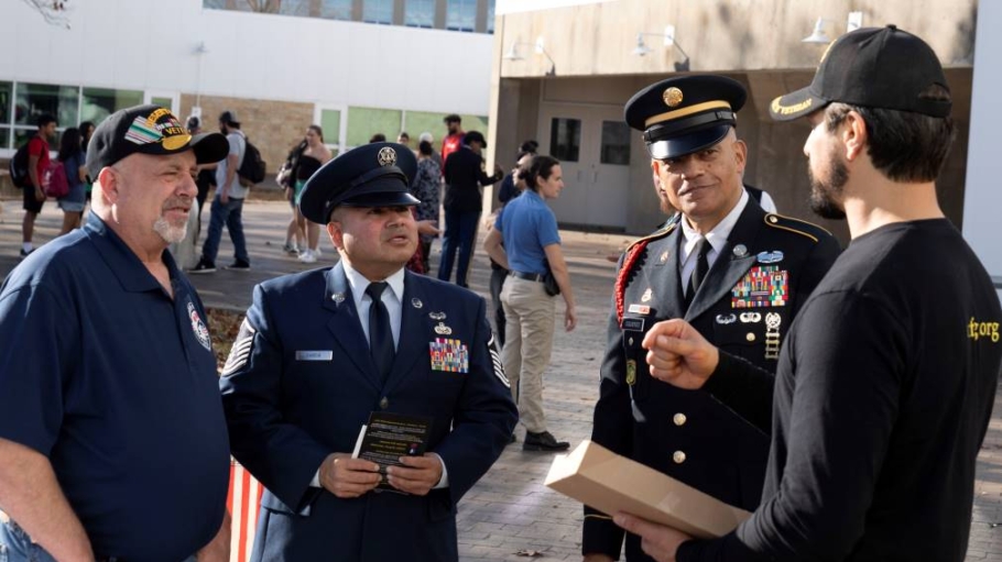 Four men talking, three in military uniforms