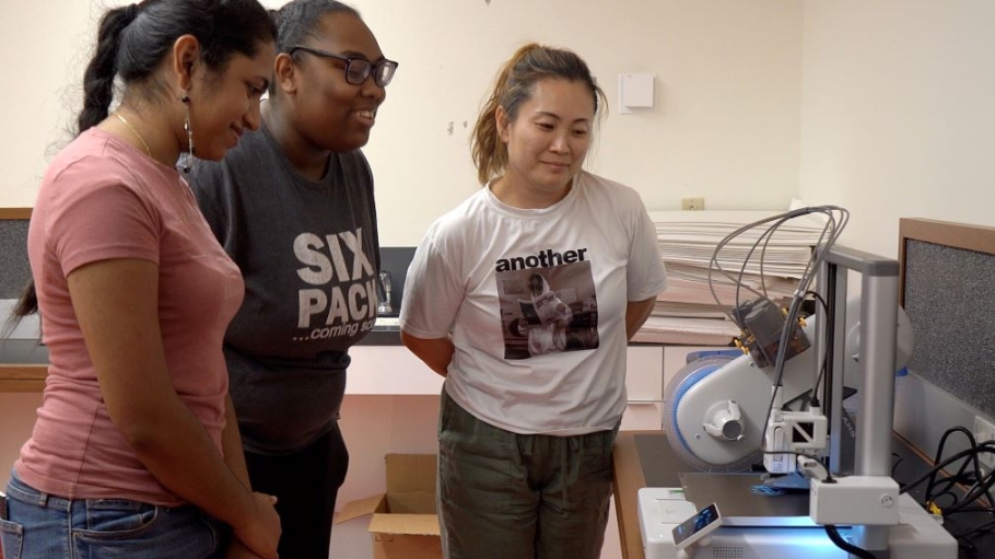 Three women working with a 3D printer
