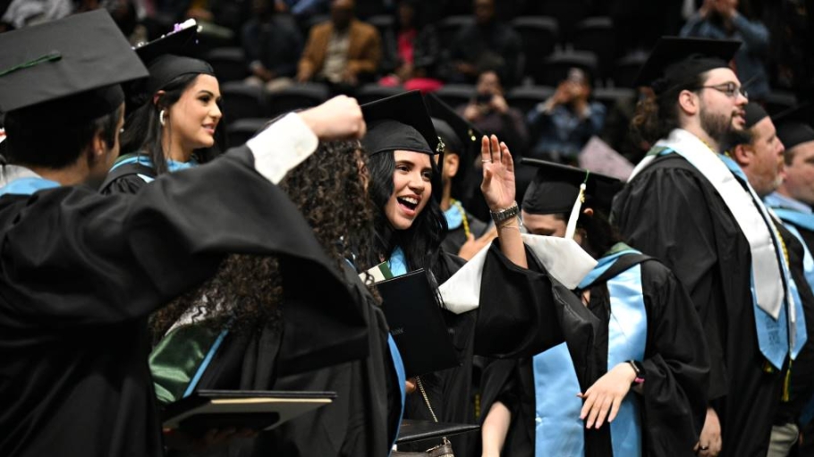 Five students in regalia moving the tassel on their mortarboards