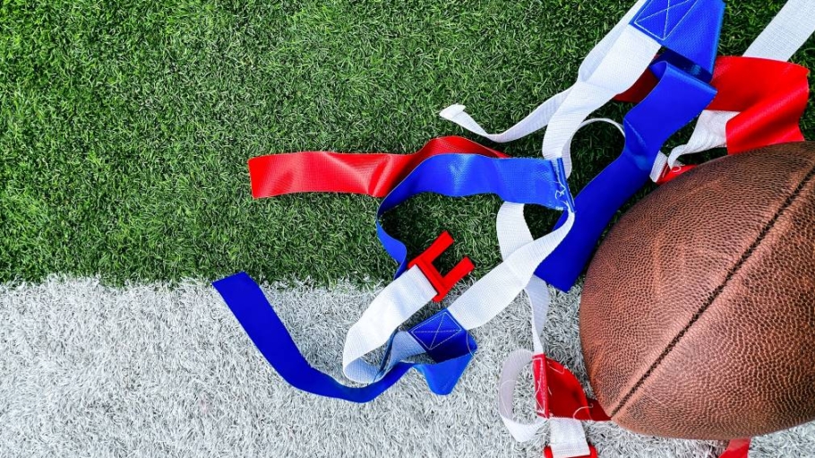 football and blue and red flags laying on a green turf field