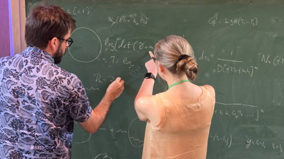 Two professors work together on a chalkboard