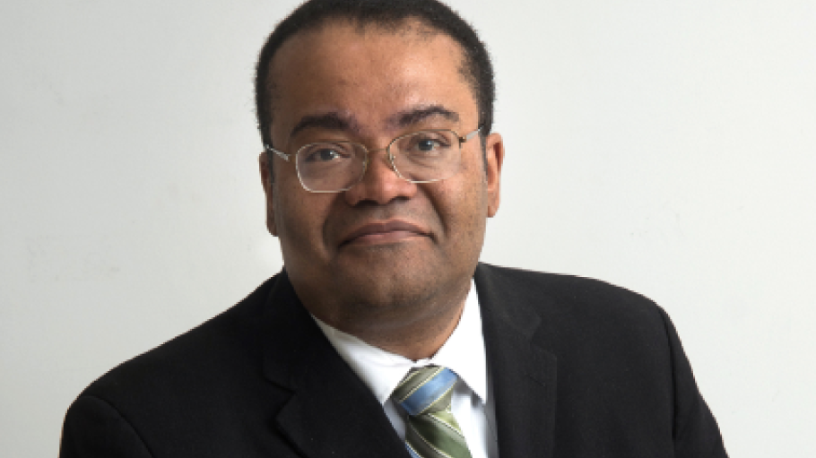 African American man with glasses in a black suit with a silver tie