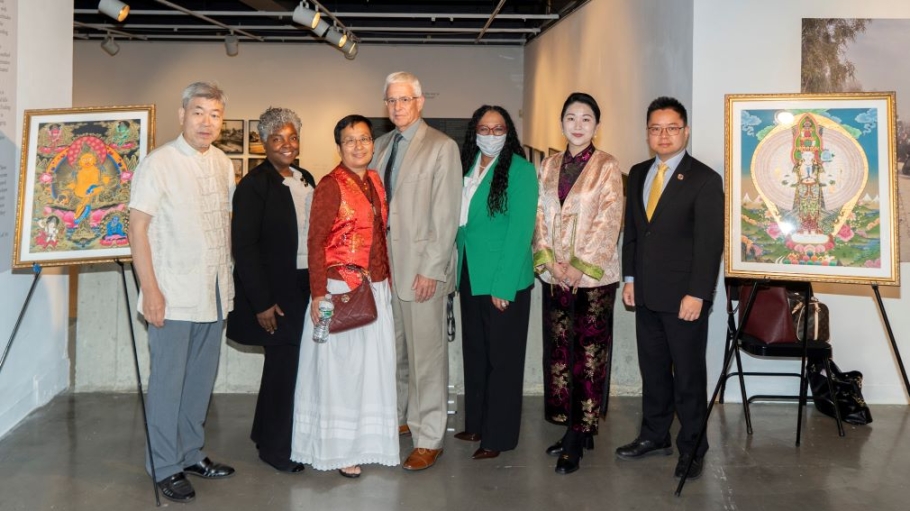 Seven people stand between two Thangka paintings