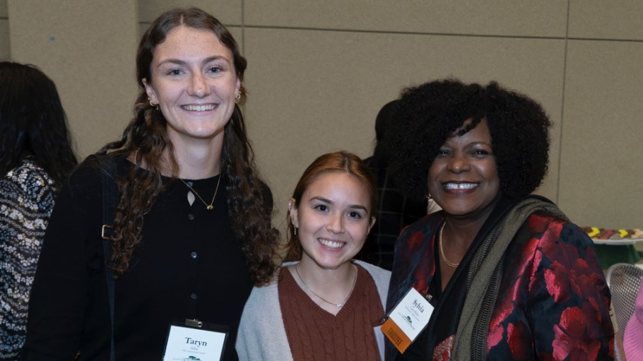 Three women in professional attire pose for a group photo
