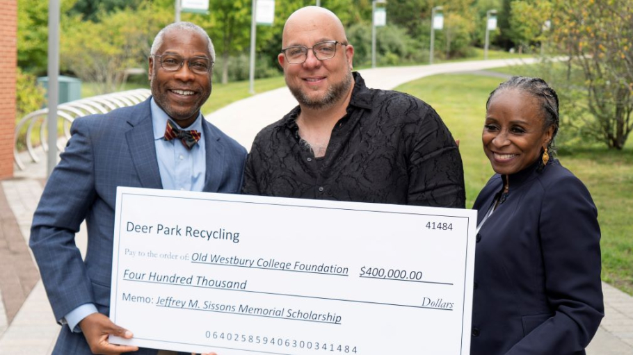 African American man and African American woman accept a mock-up donation check from Caucasian man