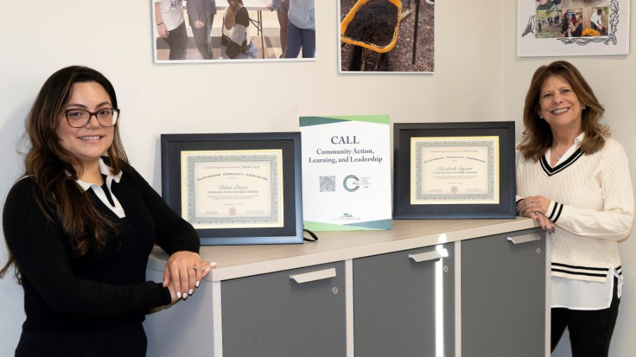 Two women in professional attire pose with certificates
