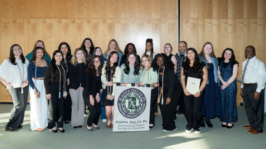 Diverse group of 20 women and two men pose for a group photo with a black and white Kappa Delta Phi banner