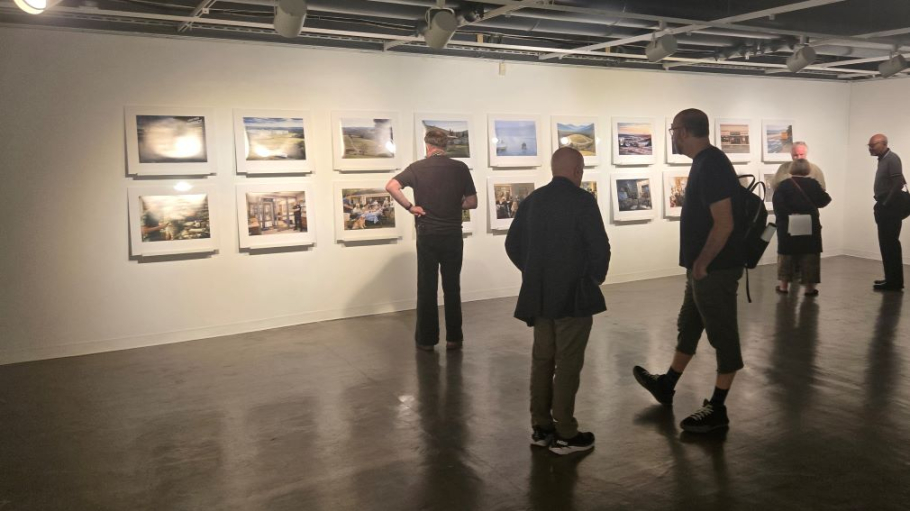 Five people looking at 14 framed images on a wall