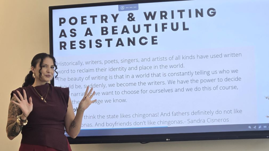 Hispanic woman standing before large screen with text reading Poetry and writing as a Beautiful Resistance