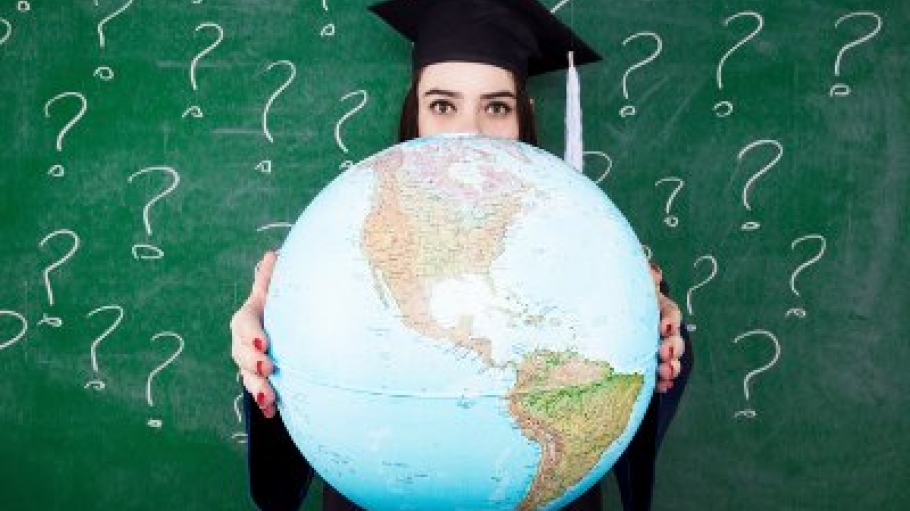 A woman in cap and gown holding a large globe