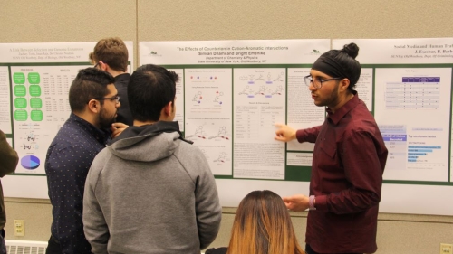 Three male students reviewing a poster presentation