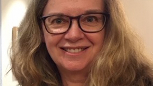 Portrait of professor Patricia Harris Caucasian woman with long wavy blonde hair and black eye glasses smiling