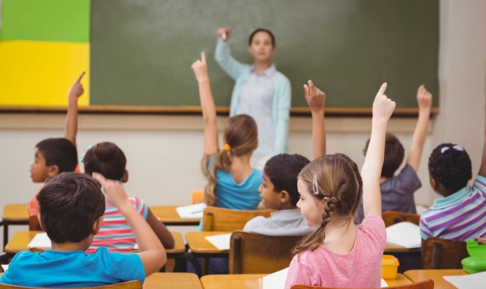 Young students raising hands to get the teacher's attention