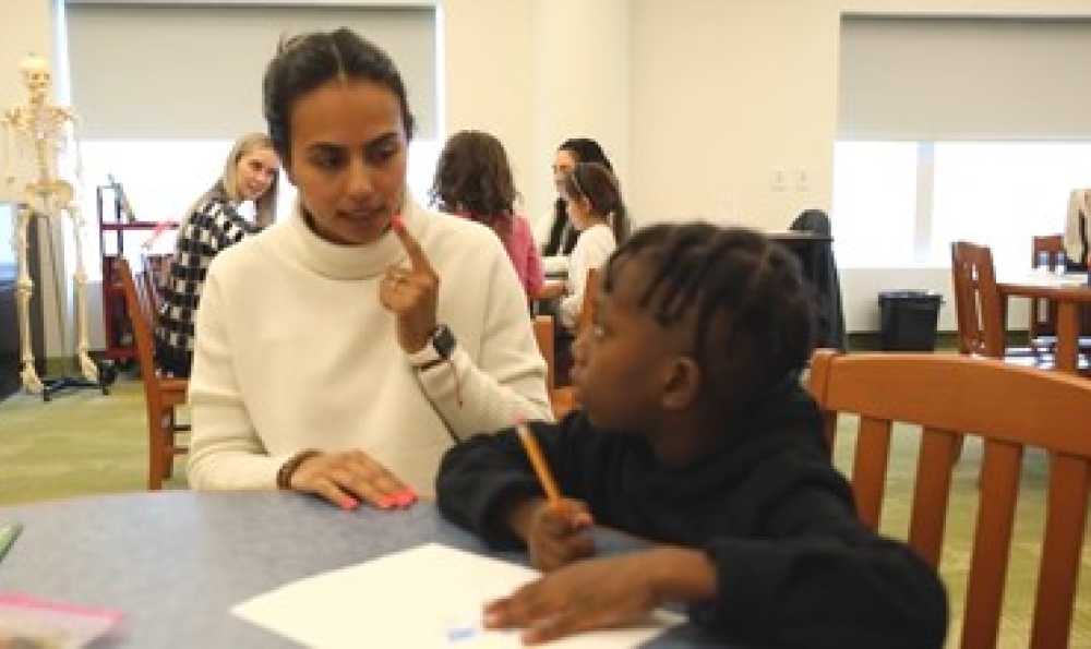 Student teacher works with make child at a table