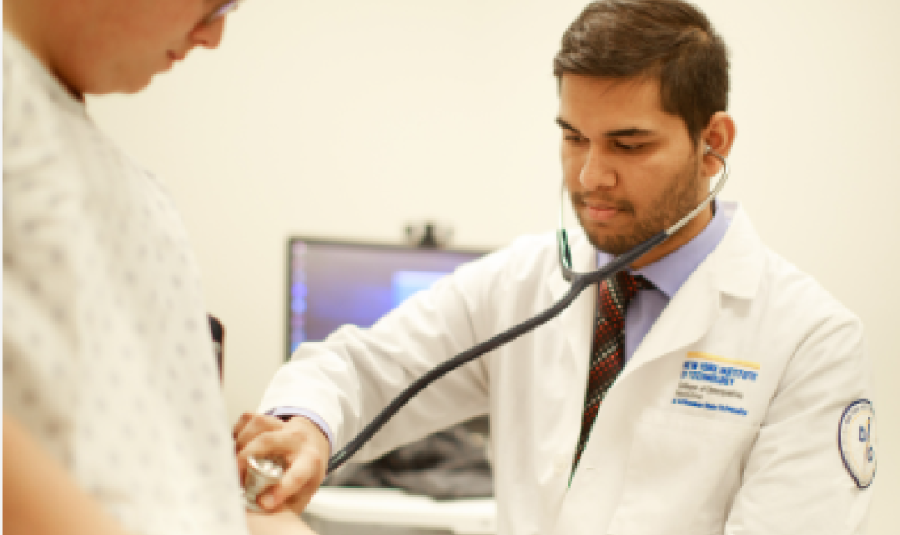 Physician in lab coat holds stethoscope to patient's arm